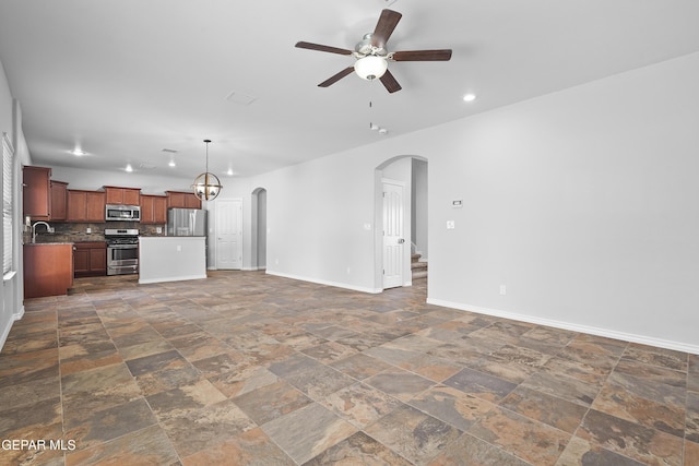 7337 Autumn Sage Dr, El Paso, TX 79911 - unfurnished living room with arched walkways, a ceiling fan, dark stone finish floors, recessed lighting, and a chandelier