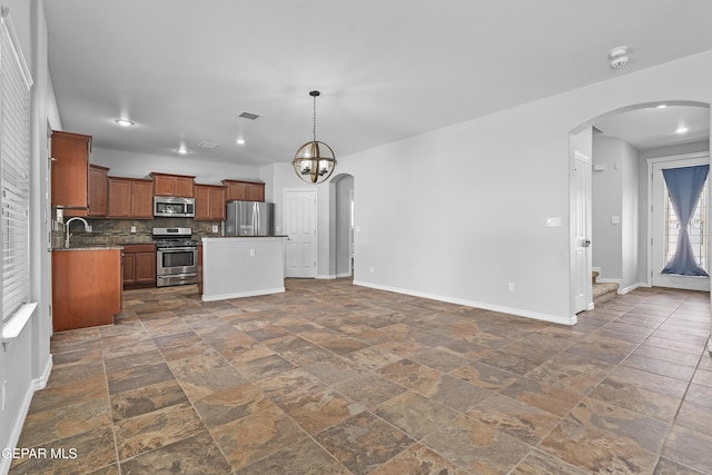 7337 Autumn Sage Dr, El Paso, TX 79911 - kitchen with stainless steel appliances, arched walkways, open floor plan, dark countertops, and decorative backsplash