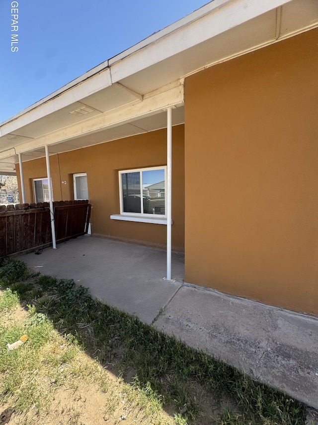 rear view of property with fence, stucco siding, and a patio area