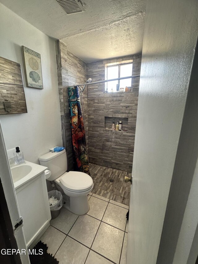 bathroom featuring visible vents, tile patterned flooring, toilet, a textured ceiling, and a shower stall