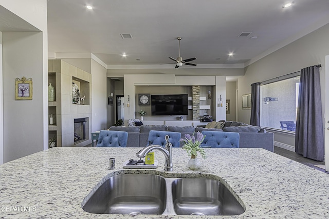 668 Darlington, El Paso, TX 79928 - kitchen featuring a tile fireplace, a ceiling fan, a sink, visible vents, and light stone countertops