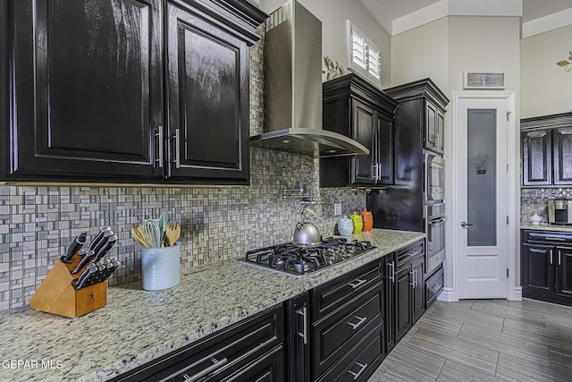 668 Darlington, El Paso, TX 79928 - kitchen with light stone countertops, dark cabinets, wall chimney exhaust hood, backsplash, and stainless steel appliances