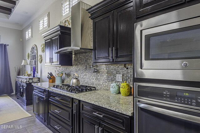 668 Darlington, El Paso, TX 79928 - kitchen featuring backsplash, stainless steel appliances, dark cabinets, and wall chimney exhaust hood