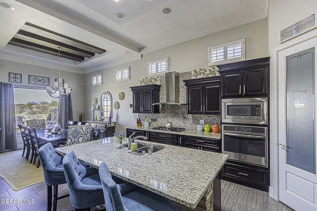 668 Darlington, El Paso, TX 79928 - kitchen with an inviting chandelier, dark cabinets, a sink, wall chimney range hood, and appliances with stainless steel finishes