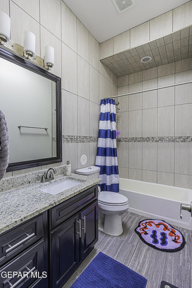 668 Darlington, El Paso, TX 79928 - full bath featuring toilet, shower / bath combo with shower curtain, tile walls, visible vents, and vanity