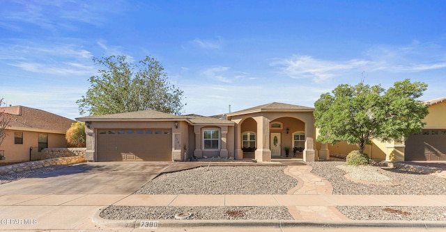 mediterranean / spanish house featuring a garage, stucco siding, and driveway