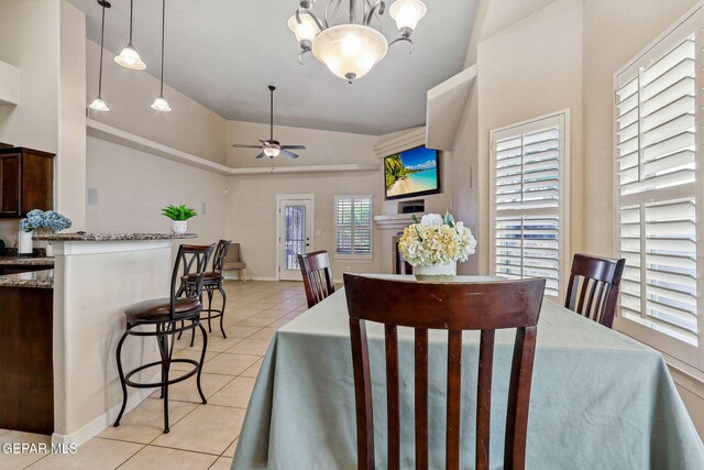dining room with lofted ceiling, light tile patterned floors, and ceiling fan with notable chandelier