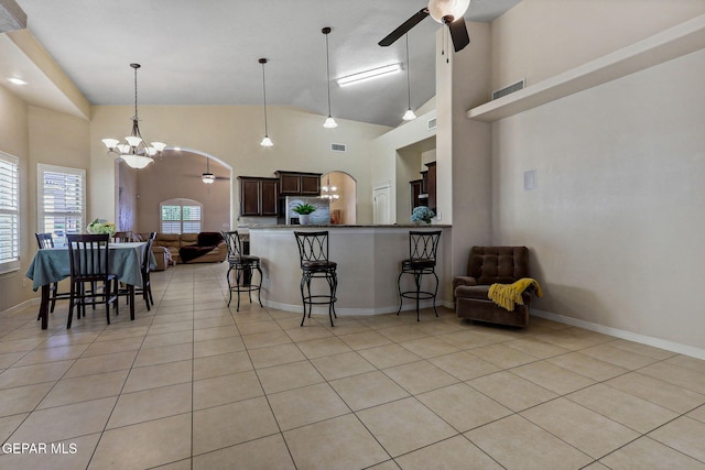 kitchen featuring light tile patterned floors, arched walkways, open floor plan, a kitchen bar, and ceiling fan with notable chandelier