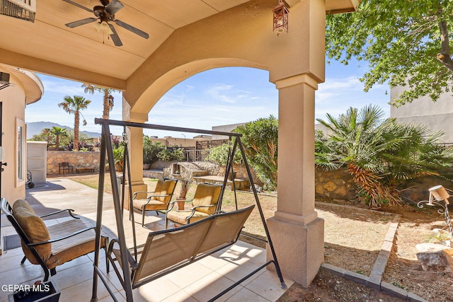 view of patio / terrace featuring a mountain view, ceiling fan, and a fenced backyard