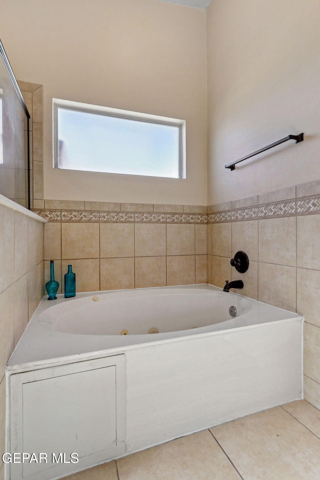 bathroom with a tub with jets and tile patterned flooring