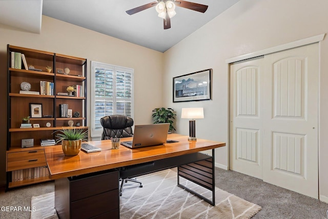 office space with a ceiling fan, vaulted ceiling, light carpet, and baseboards