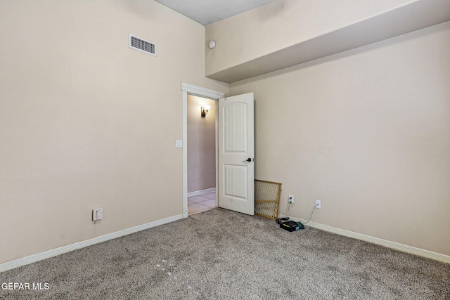 empty room with carpet flooring, visible vents, and baseboards