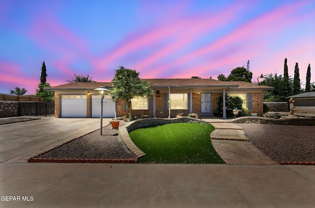 ranch-style home with a garage, a lawn, concrete driveway, and brick siding