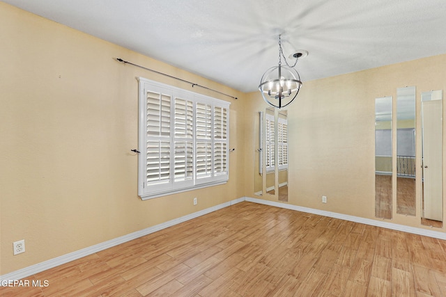 unfurnished dining area featuring an inviting chandelier, baseboards, and wood finished floors