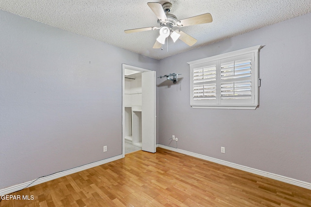 unfurnished bedroom featuring baseboards, a textured ceiling, ceiling fan, and wood finished floors