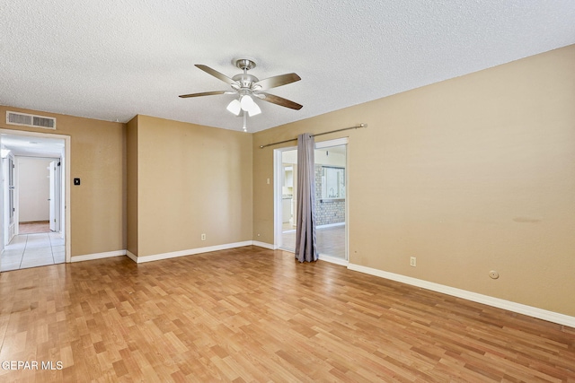 unfurnished room featuring light wood-style floors, baseboards, ceiling fan, and visible vents