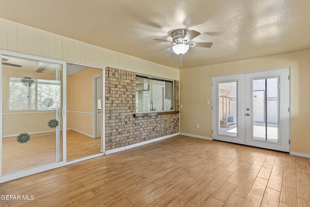 spare room with baseboards, a ceiling fan, french doors, and light wood finished floors