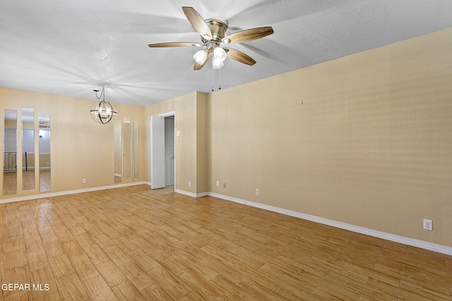 empty room with a textured ceiling, baseboards, light wood finished floors, and ceiling fan with notable chandelier