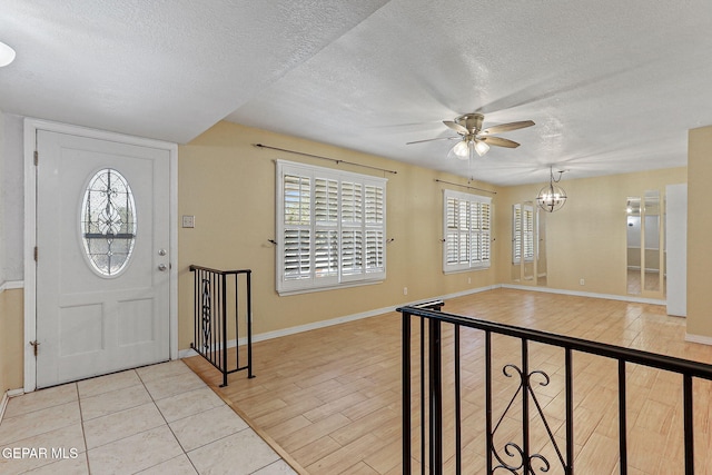foyer entrance with baseboards, light wood-style flooring, a ceiling fan, and a textured ceiling