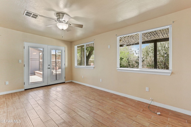 unfurnished room featuring ceiling fan, visible vents, french doors, and light wood-style floors