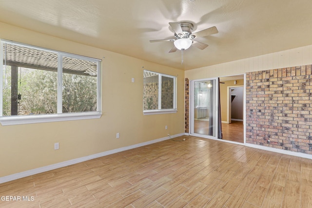 empty room with baseboards, a ceiling fan, and light wood-style floors