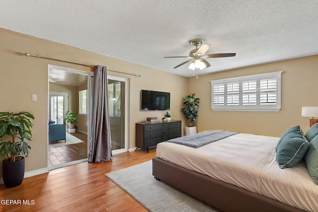 bedroom featuring baseboards, a textured ceiling, wood finished floors, and multiple windows