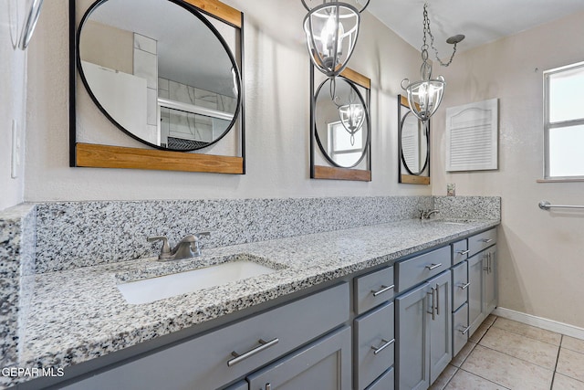 bathroom with baseboards, a sink, tile patterned floors, and double vanity