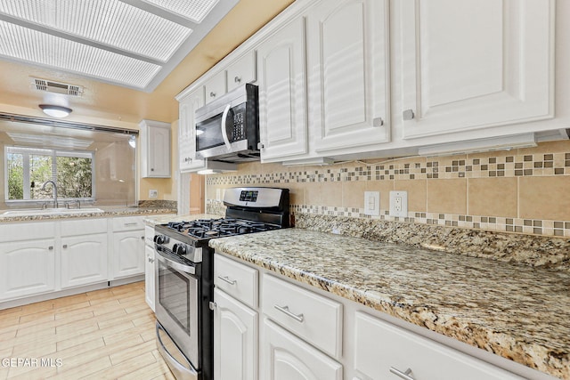 kitchen featuring white cabinets, appliances with stainless steel finishes, a sink, and visible vents