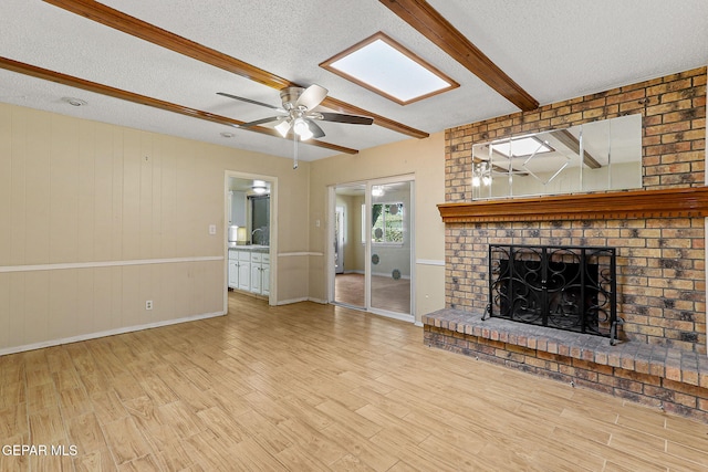 unfurnished living room with beamed ceiling, a ceiling fan, a textured ceiling, and wood finished floors