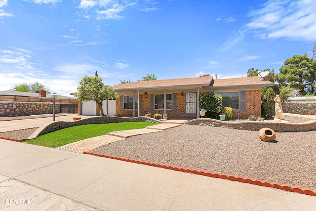 single story home with fence, brick siding, an attached garage, driveway, and a porch