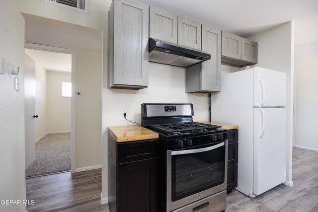 5201 Capistrano Dr, El Paso, TX 79924 - kitchen with under cabinet range hood, light wood-style floors, visible vents, stainless steel gas stove, and freestanding refrigerator