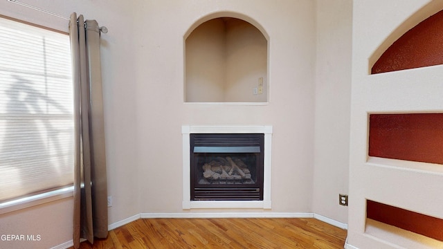 2088 Crystal Ridge St, El Paso, TX 79938 - unfurnished living room with baseboards, a glass covered fireplace, and wood finished floors