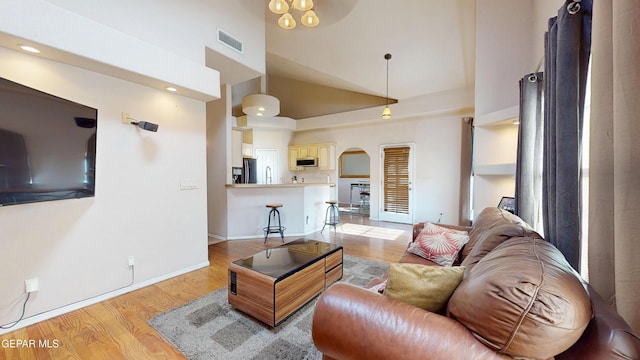 2088 Crystal Ridge St, El Paso, TX 79938 - living area featuring visible vents, baseboards, high vaulted ceiling, arched walkways, and light wood finished floors