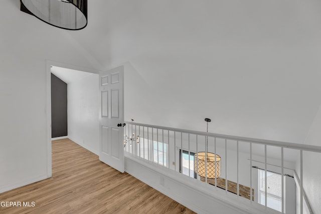 corridor featuring a chandelier, light wood-style floors, plenty of natural light, and baseboards