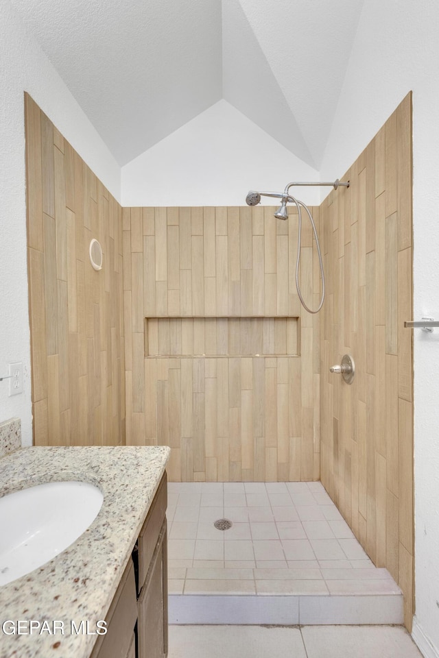 full bathroom with vanity, lofted ceiling, and a tile shower