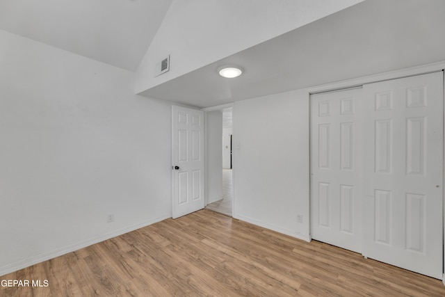 unfurnished bedroom with a closet, high vaulted ceiling, visible vents, light wood-style flooring, and baseboards