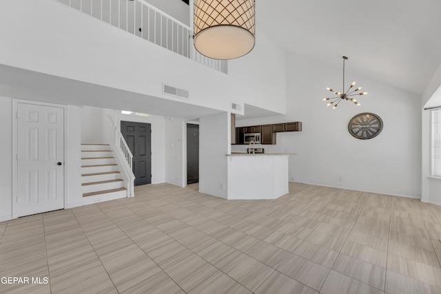 unfurnished living room with a notable chandelier, stairs, visible vents, and high vaulted ceiling