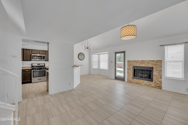 unfurnished living room with a fireplace, a chandelier, light tile patterned flooring, and vaulted ceiling