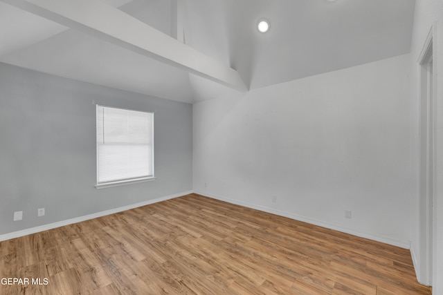 empty room featuring vaulted ceiling, baseboards, and wood finished floors
