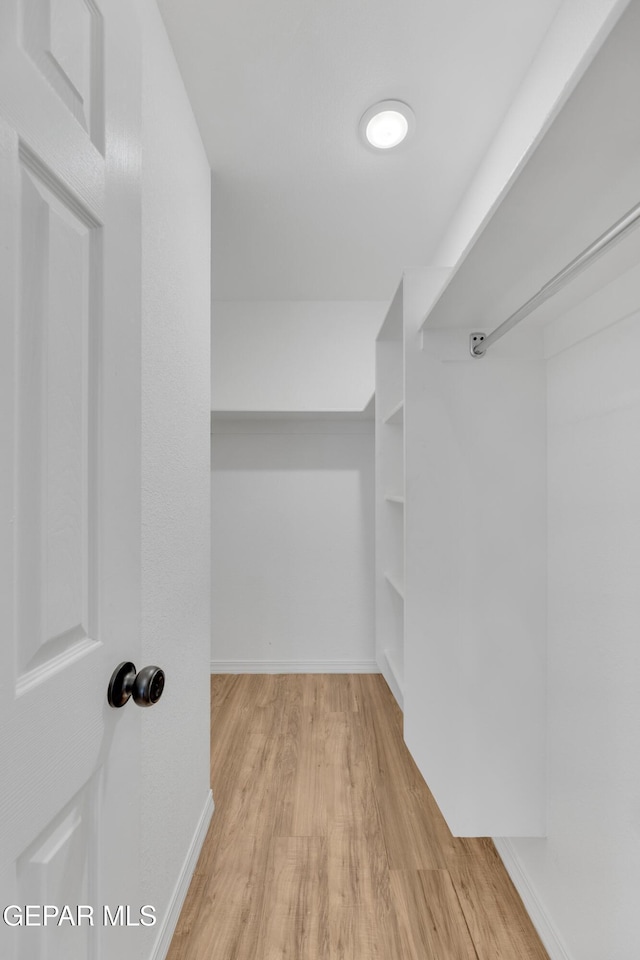 walk in closet with wood finished floors