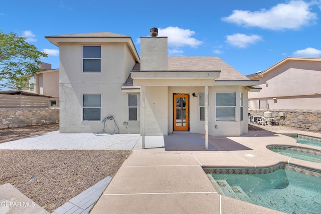 back of house featuring an in ground hot tub, a fenced in pool, stucco siding, and a patio
