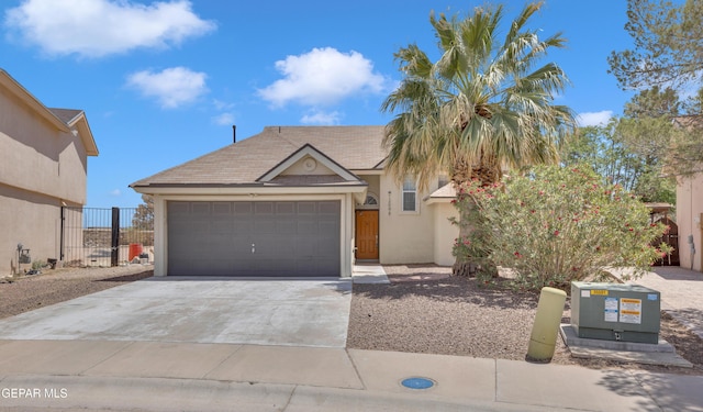 view of front of home featuring concrete driveway, a garage, stucco siding, and fence
