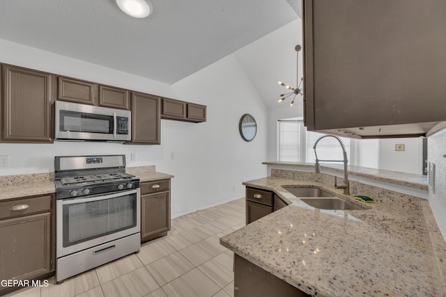 kitchen featuring light tile patterned floors, a sink, appliances with stainless steel finishes, light stone counters, and lofted ceiling