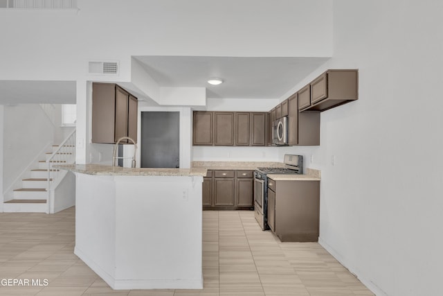 kitchen with visible vents, a peninsula, appliances with stainless steel finishes, and a sink