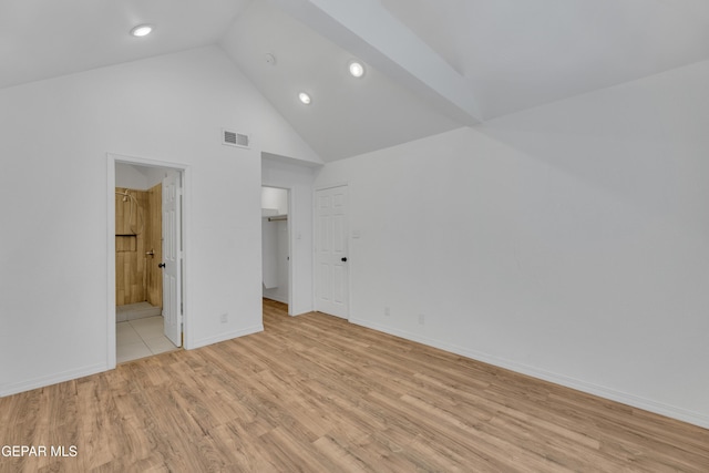 unfurnished bedroom with baseboards, visible vents, connected bathroom, high vaulted ceiling, and light wood-style floors