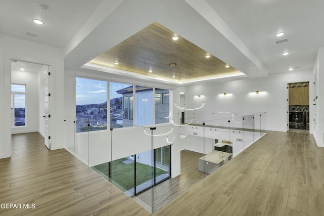 interior space featuring recessed lighting, baseboards, wood finished floors, and a tray ceiling