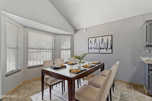 dining area with stone finish flooring, vaulted ceiling, and baseboards