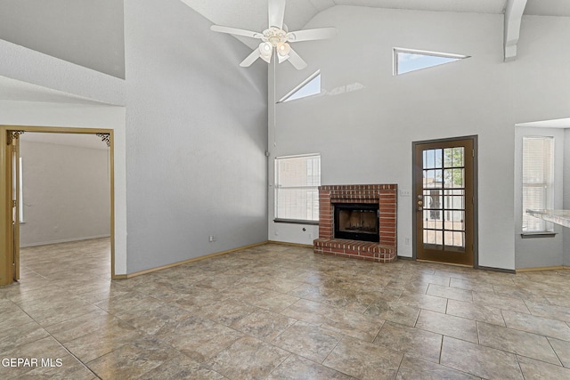 unfurnished living room featuring stone finish floor, baseboards, a brick fireplace, a ceiling fan, and high vaulted ceiling