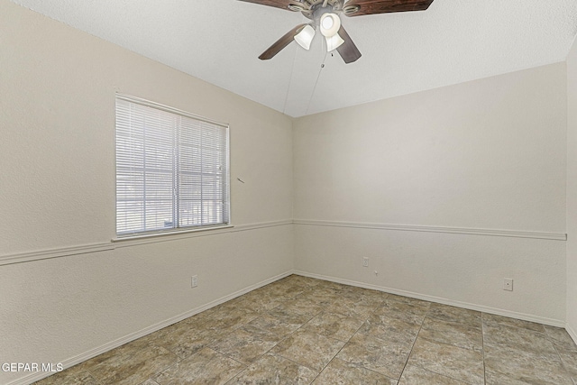 empty room featuring ceiling fan and baseboards