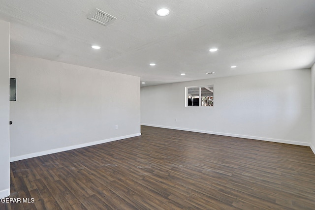 empty room featuring dark wood finished floors, visible vents, and baseboards